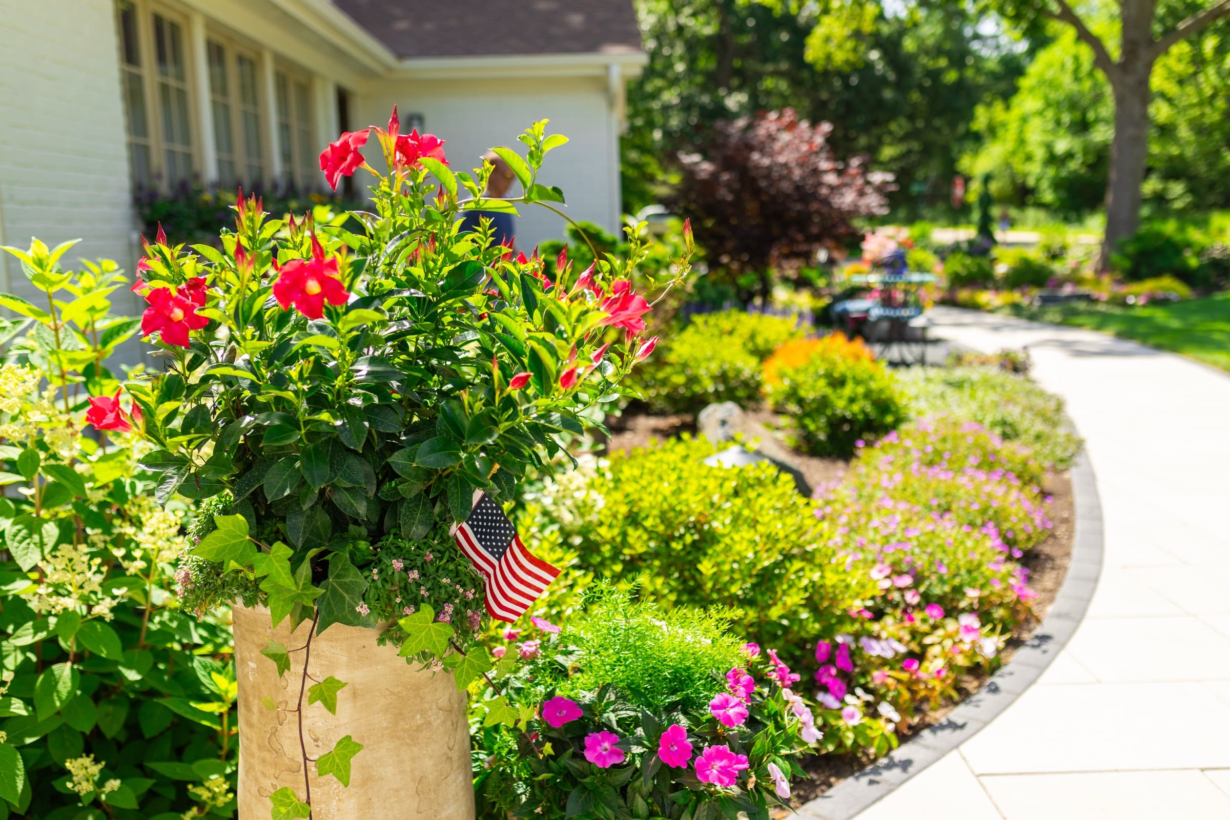 A planted stone urn and winding paver walkway through the garden
