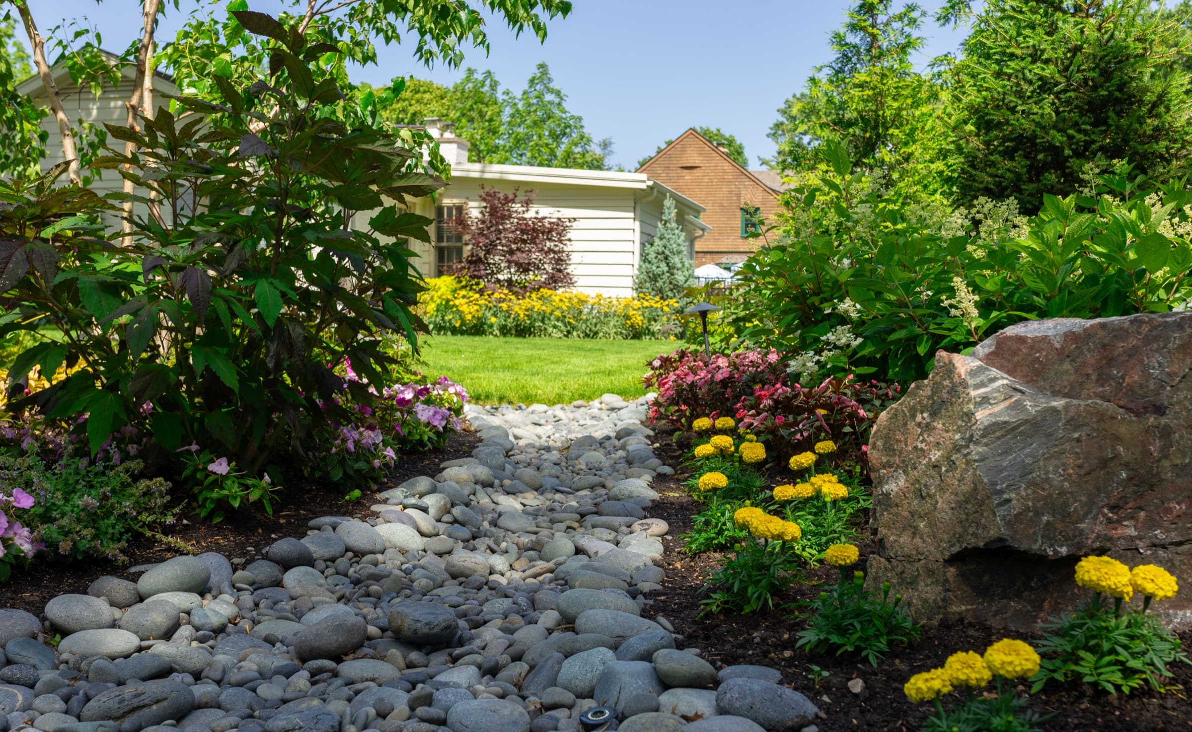A river-rock dry creek bed accented with boulders and landscape lighting
