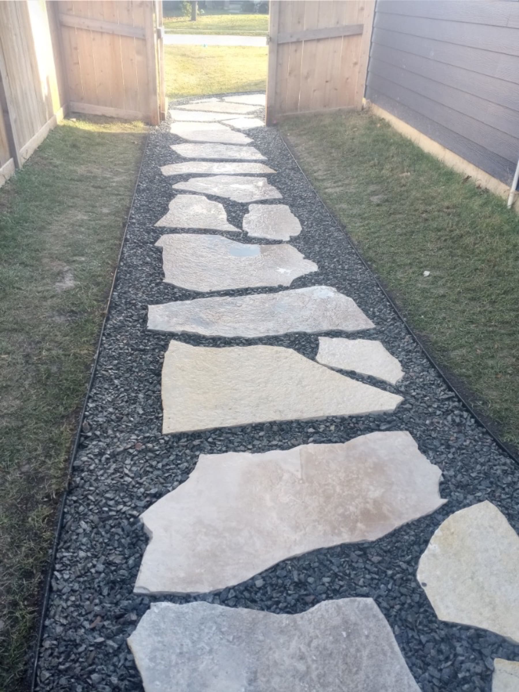 A natural flagstone path set in dark gravel between two garden gates