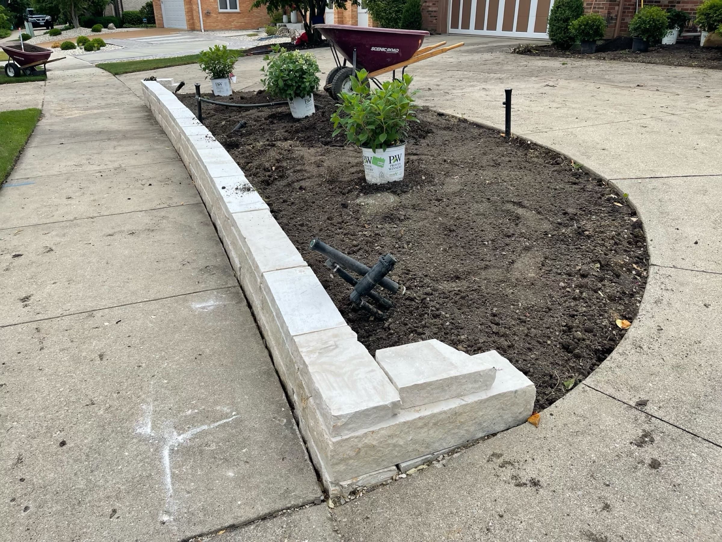 A curved limestone retaining wall and freshly prepared planting bed